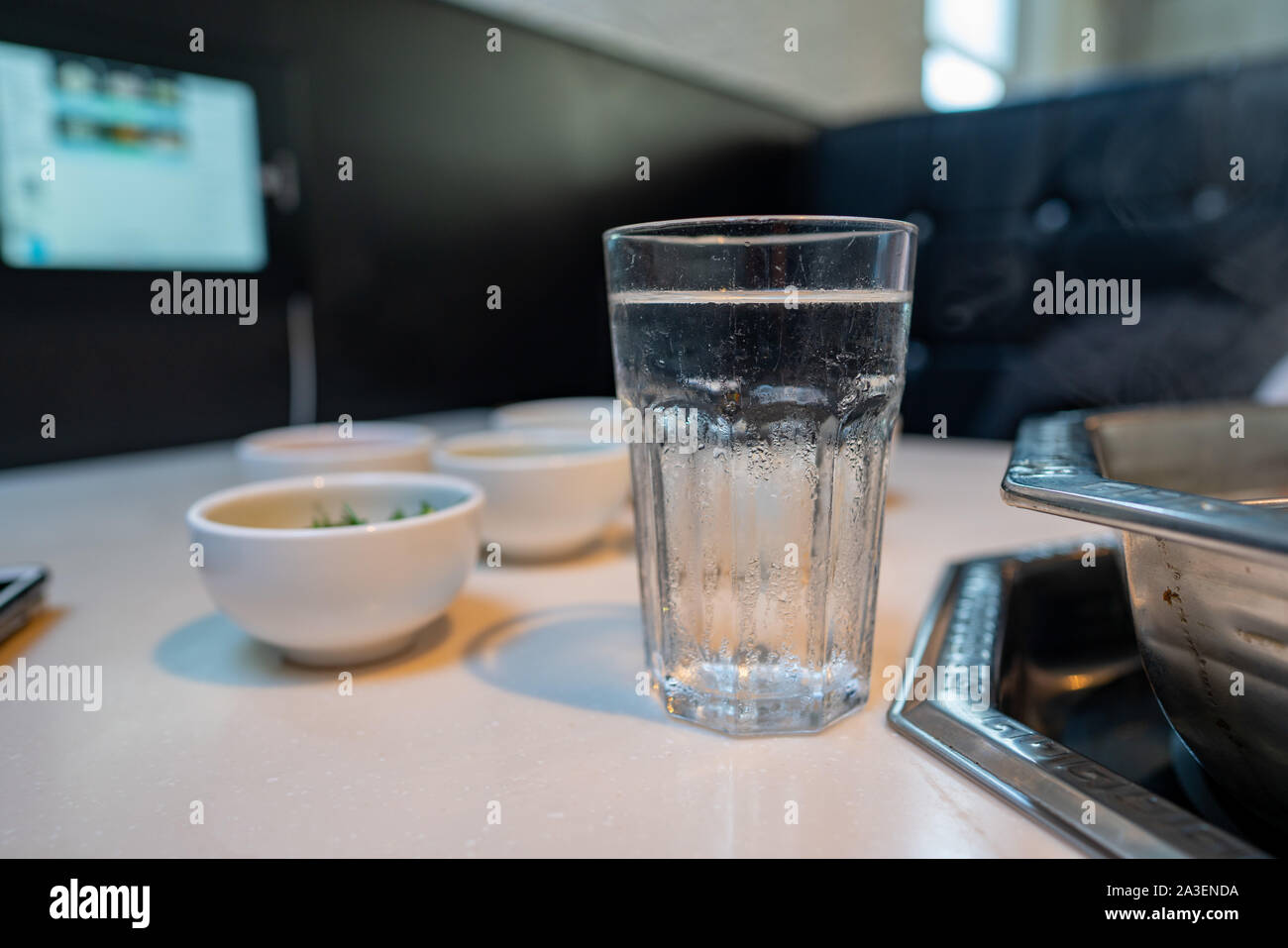 Verre de l'eau assis dans restaurant avec divers bols et hot pot Banque D'Images