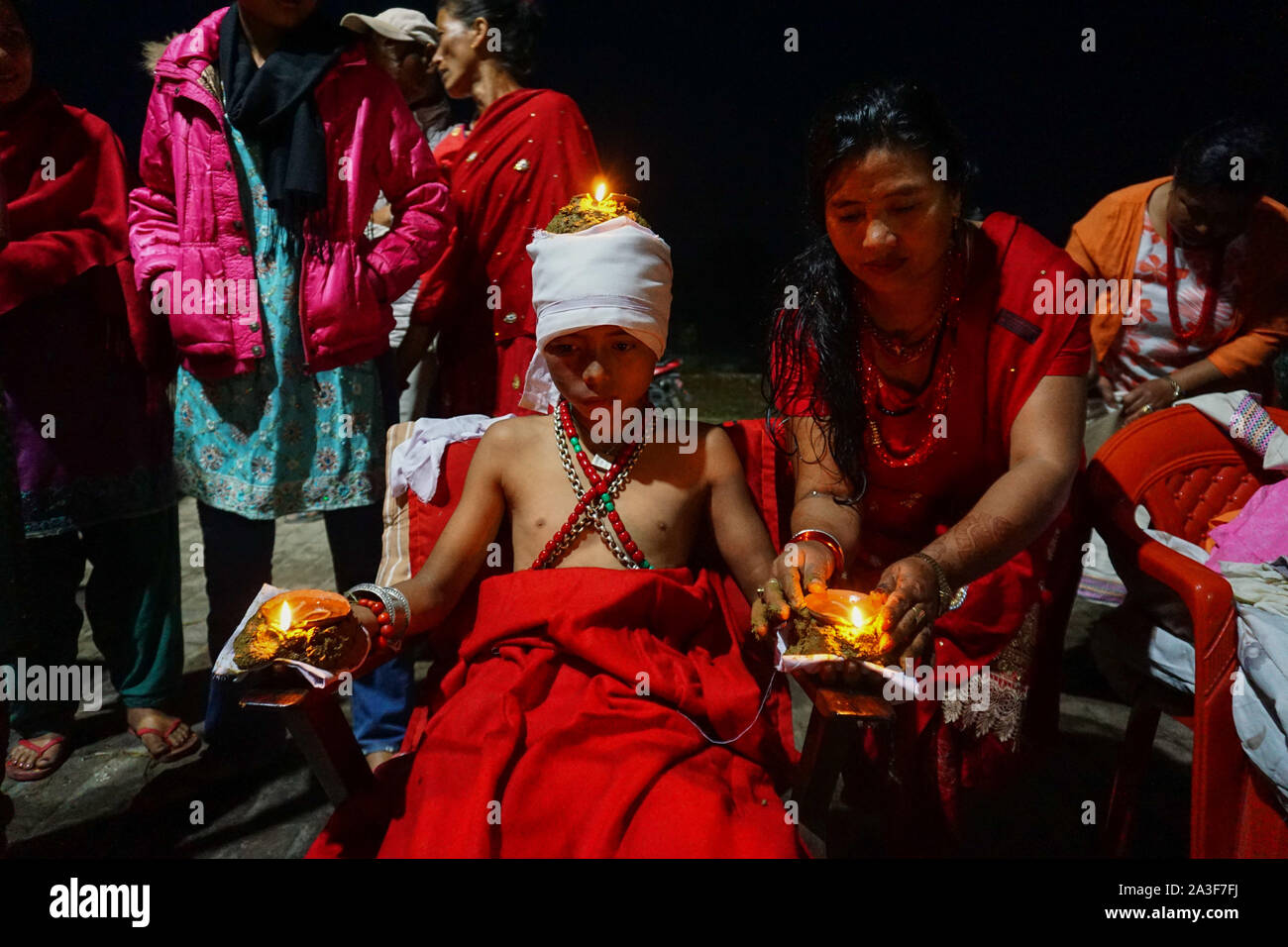 Bhaktapur, Népal. 05Th Oct, 2019. Une femme népalaise lights lampes à huile sur le corps d'un hindou dévot pendant le festival.Dashain est célébré pour marquer la victoire d'après des écrits religieux hindou de Ramayan sur le mal roi démon Ravana et plus le démon Mahisasur qui terrorise les habitants de cruellement dans l'Inde sous forme d'un buffle d'eau qui fait rage. Credit : SOPA/Alamy Images Limited Live News Banque D'Images