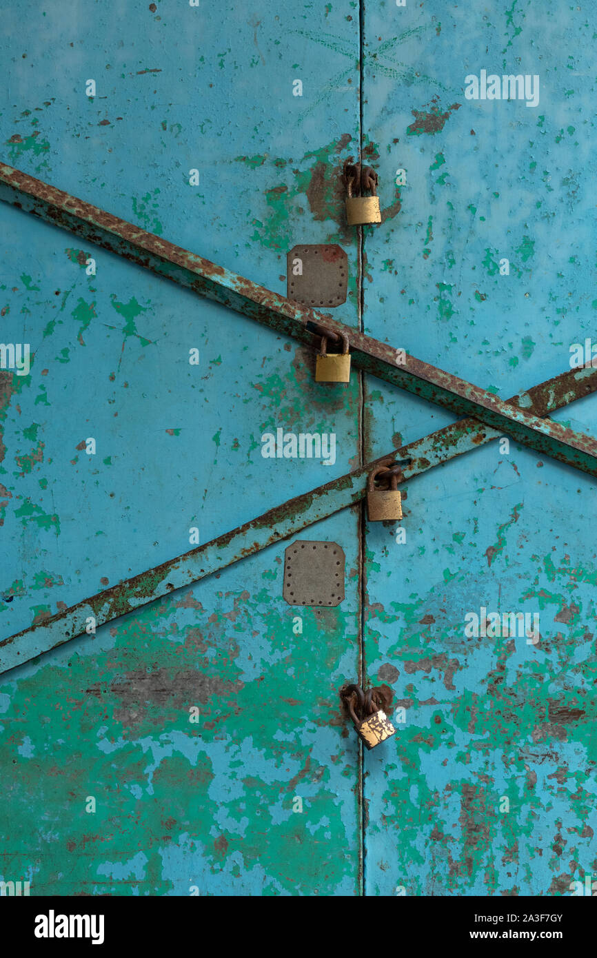 Vieille porte peinte Grungy verrouillé avec plusieurs cadenas, full frame Banque D'Images