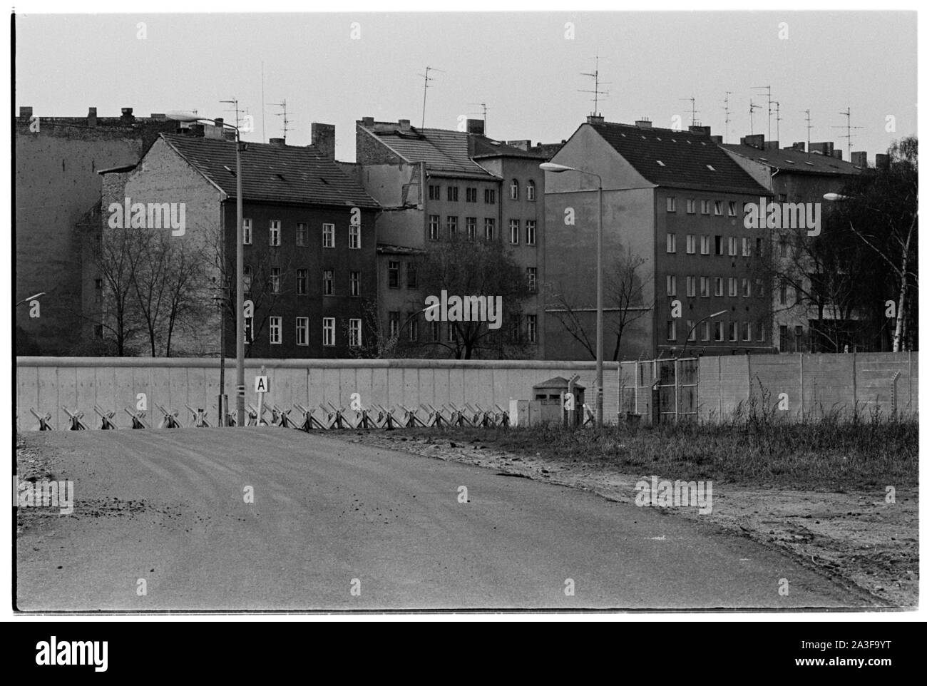 Voir à travers le no man's land du mur de Berlin, de l'Est à l'Ouest dans le domaine de la Friedrichstrasse, une petite figure indistincte, peut être vu à l'une des fenêtres d'un bâtiment sur la droite de la photo. La photo montre la terre ratissée, et le réservoir de condensats dans la distance la plus proche du mur. Banque D'Images