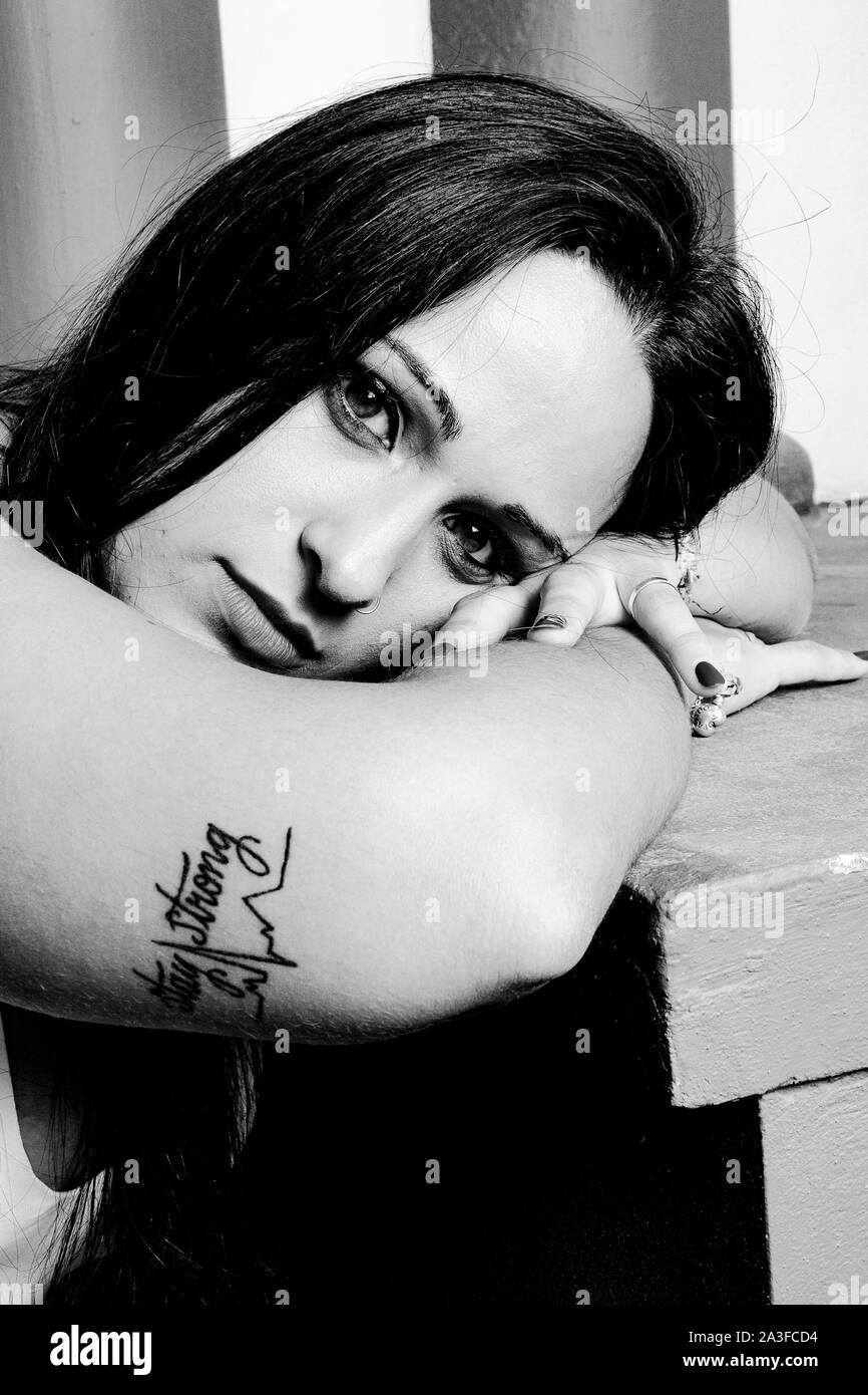 Éclairage studio portrait of a young woman leaning, avec un tatouage, de rester fort Banque D'Images