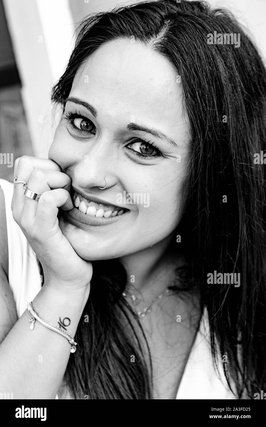 Portrait d'une jeune femme, avec sa main posée sur sa bouche, tandis que de mordre ses ongles smiling Banque D'Images