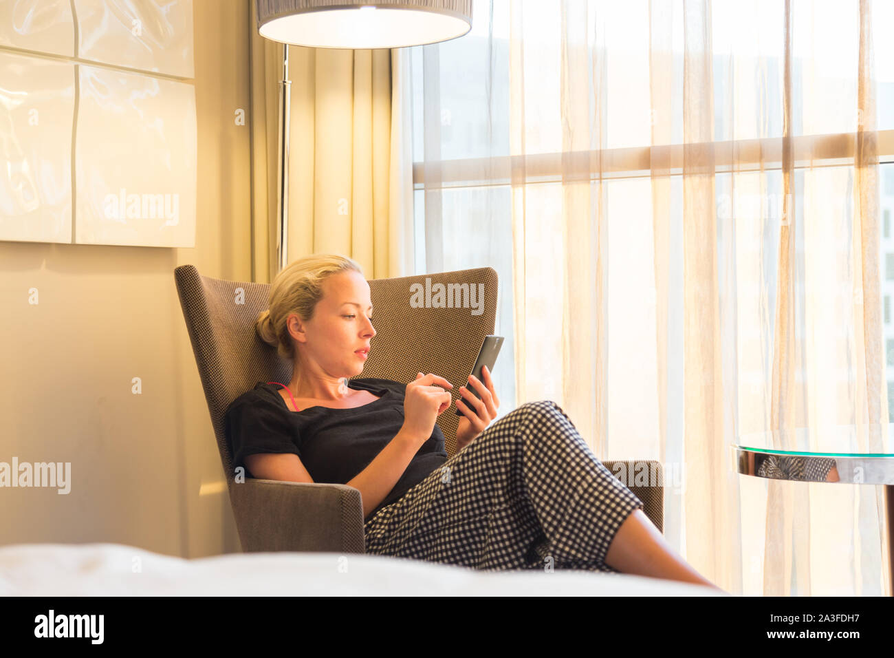 Portrait d'un voyage d'affaires, lassés d'une rencontre d'affaires, assise seule dans la chambre d'hôtel afterwork, lire et répondre aux e-mails et messages sur Banque D'Images