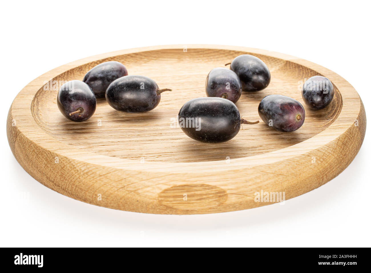 Beaucoup d'entiers et frais, raisin noir sur plaque de bambou isolé sur fond blanc Banque D'Images