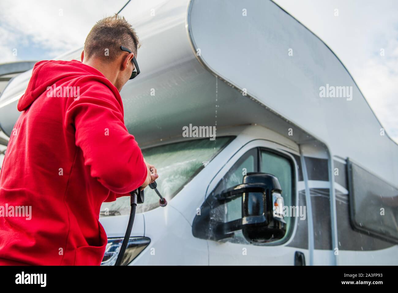 Les hommes de race blanche de laver ses RV Camping Camping-car de classe C à l'aide de la rondelle de pression. Thème de l'industrie du voyage. Banque D'Images
