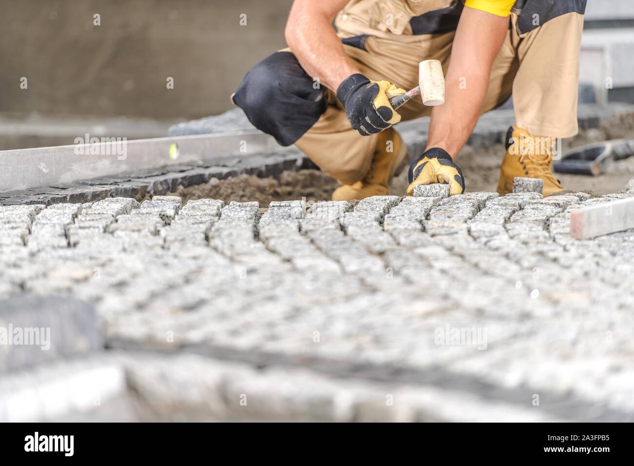 Brique de pavage allée résidentielle par travailleur professionnel du Caucase. L'industrie de la construction. Banque D'Images