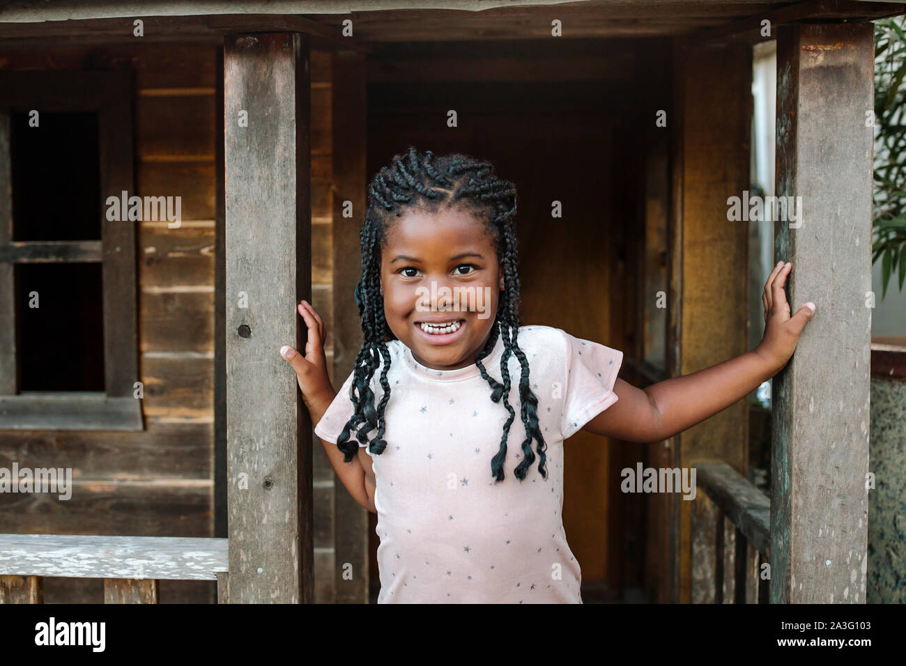 Young smiling black girl with braids sur portique de bois chalet Banque D'Images