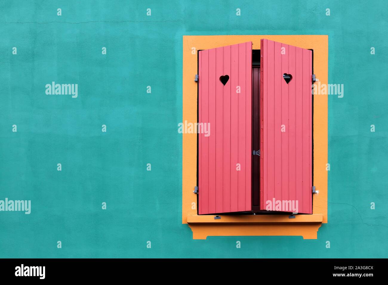 Fenêtre avec volets rouges et des petits cœurs sur un mur vert Banque D'Images