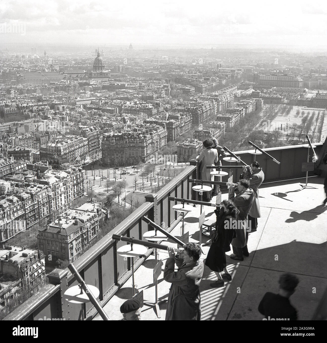 Années 1950, historiques, les gens sur la plate-forme en bois en haut de la Tour Eiffel en utilisant les 20 'franc' Longues-Vues ou télescopes pour regarder au-dessus de la ville de Paris, France. Banque D'Images