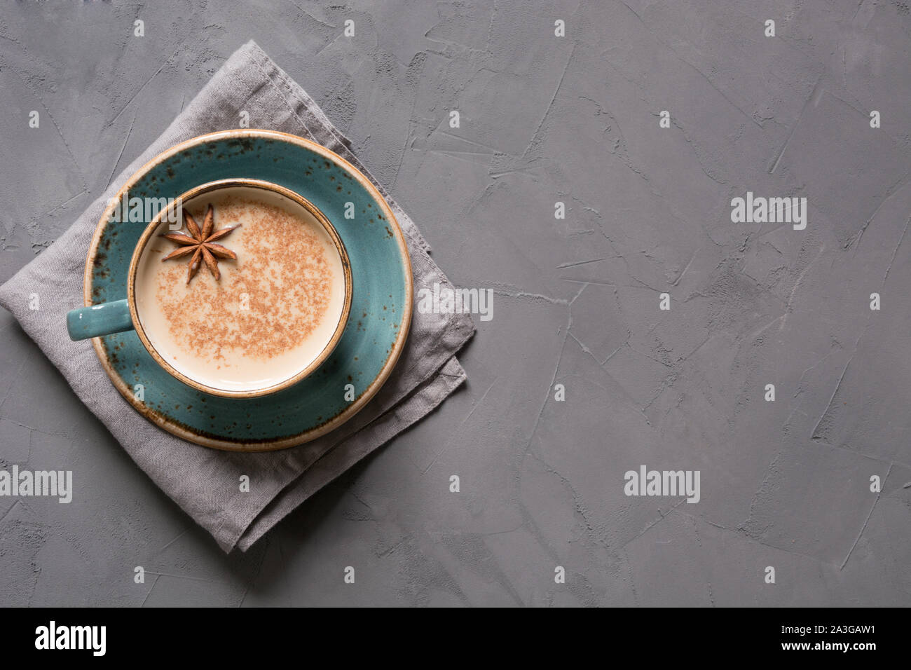 Indien Masala thé ou café dans la Tasse bleue avec des épices et de la cannelle sur table béton noir. Vue d'en haut. Banque D'Images