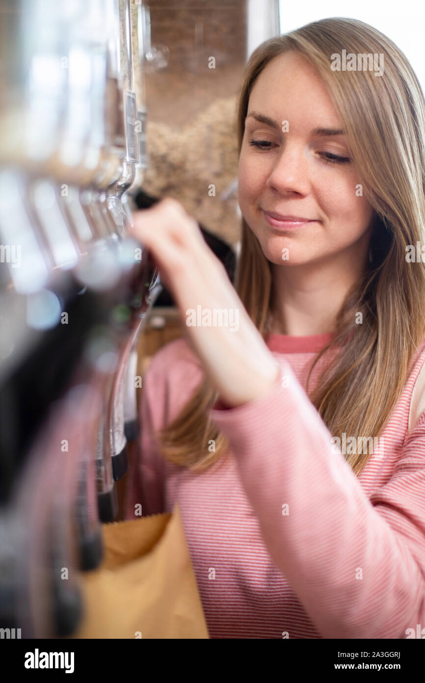 Femme Sac en papier à partir de remplissage Distributeur pour les grains et les céréales dans l'épicerie de plastique Banque D'Images