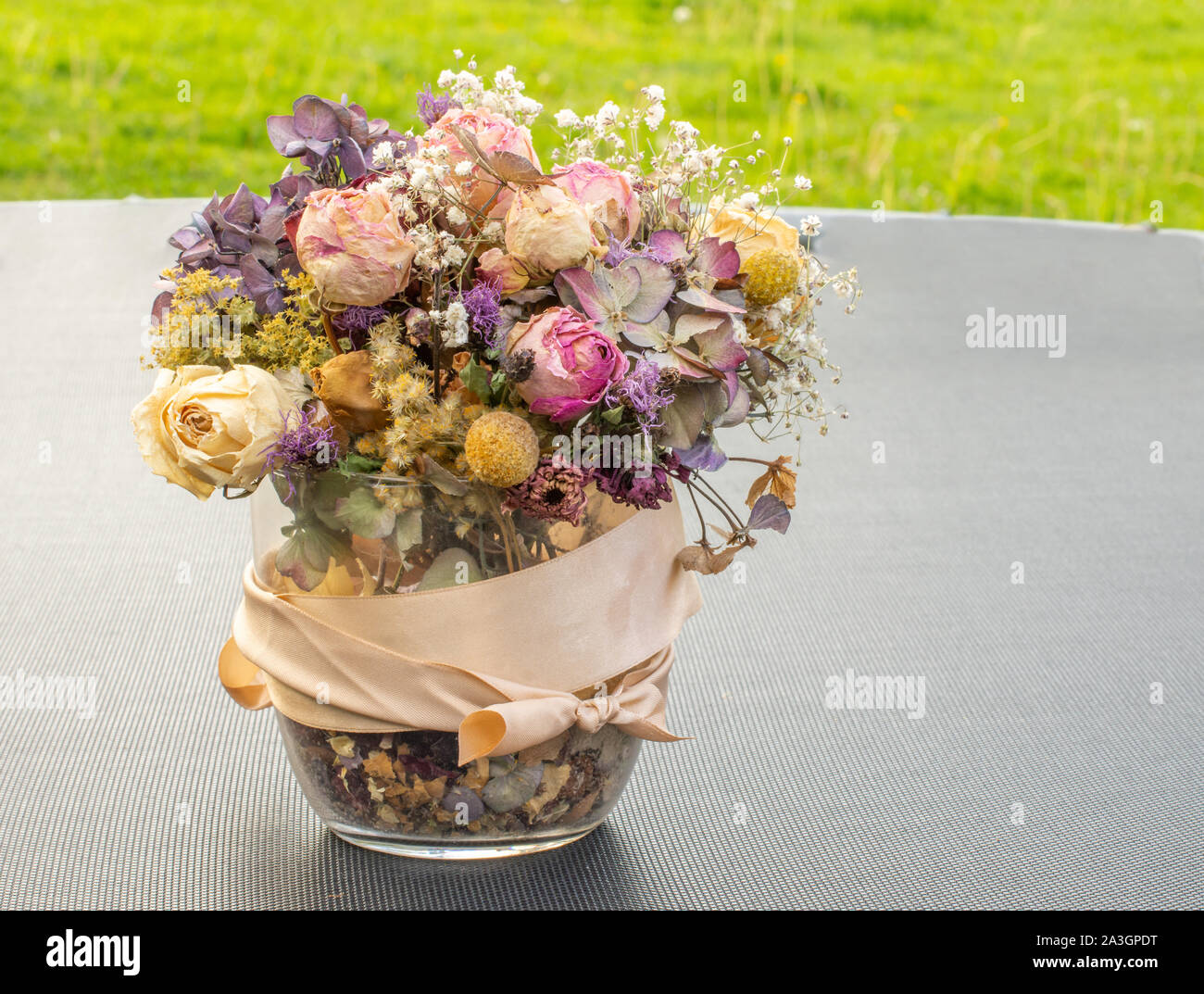 Fleurs sèches dans un vase en verre sur la table noire avec de l'herbe vert vif pour l'arrière-plan. Bouquet fait maison avec des fleurs sèches. Photo extérieur Banque D'Images