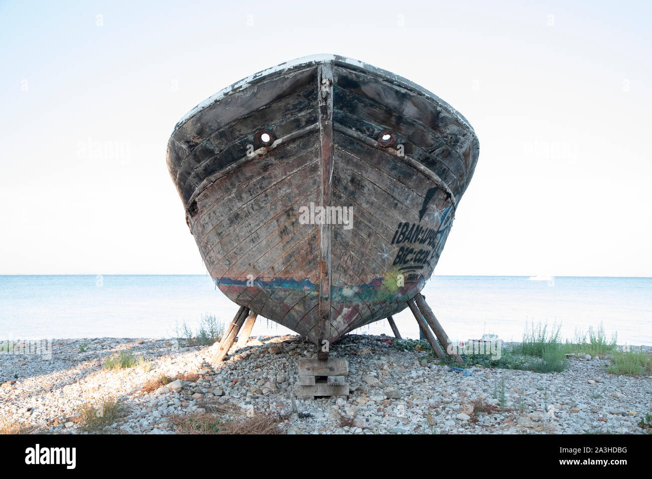 Un vieux bateau de pêche en bois couvert de graffitis sur cale sèche. Banque D'Images