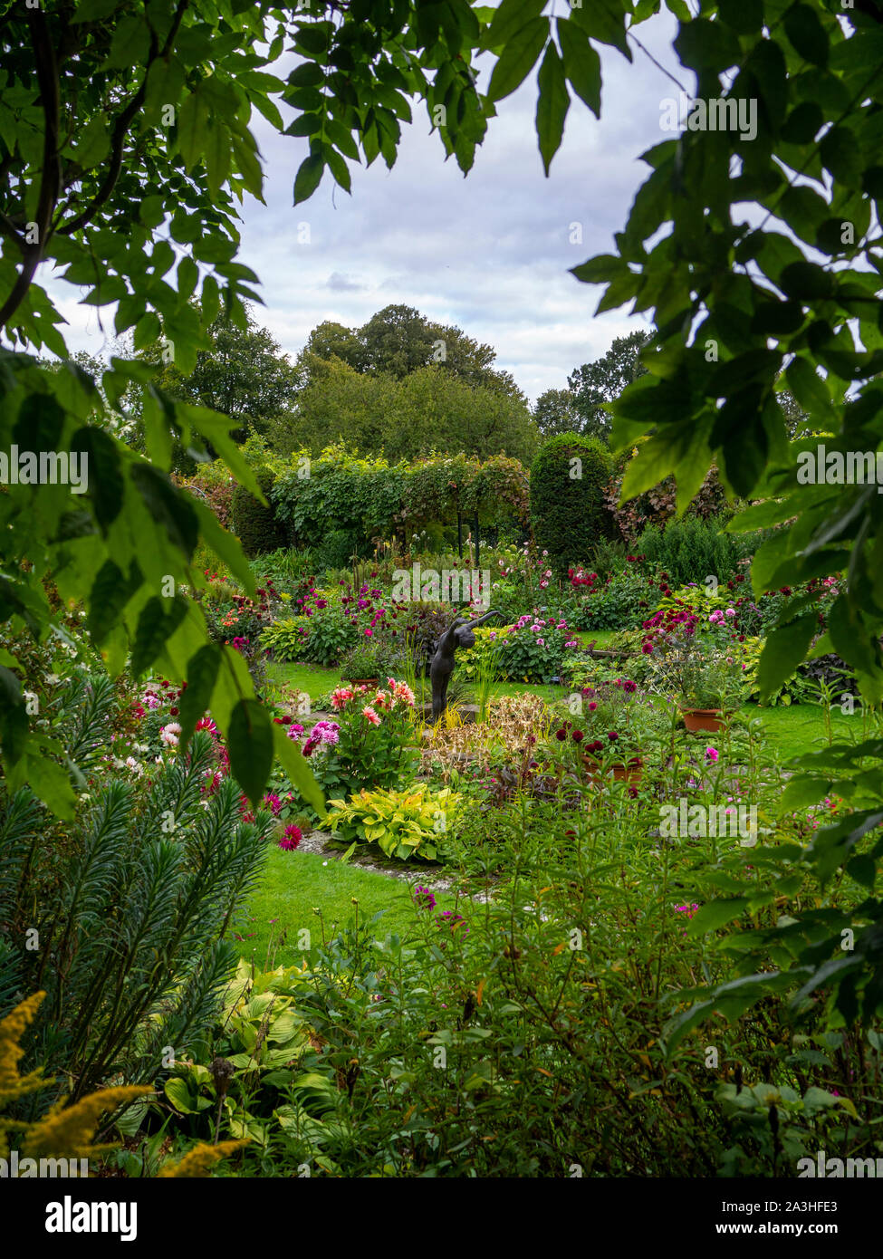 Chenies Manor sunken garden à Dahlia temps, encadré par une glycine de serrure. L'étang ornemental dispose dans le jardin en contrebas avec la sculpture.. Banque D'Images
