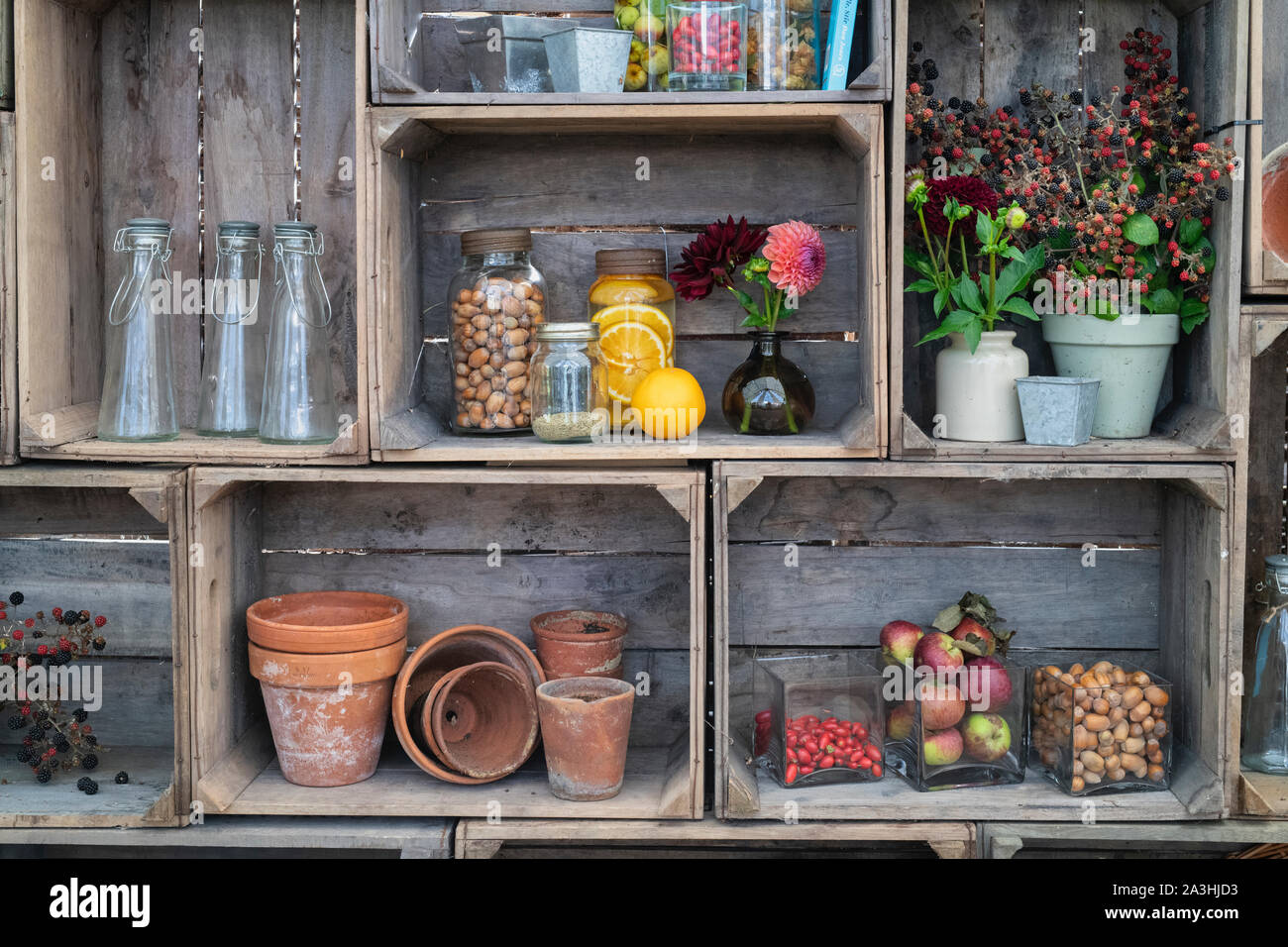 Pots de gin au four à l'ancienne infusés de fruits et de noix avec vases de fleurs coupées dans une caisse en bois, Royaume-Uni Banque D'Images