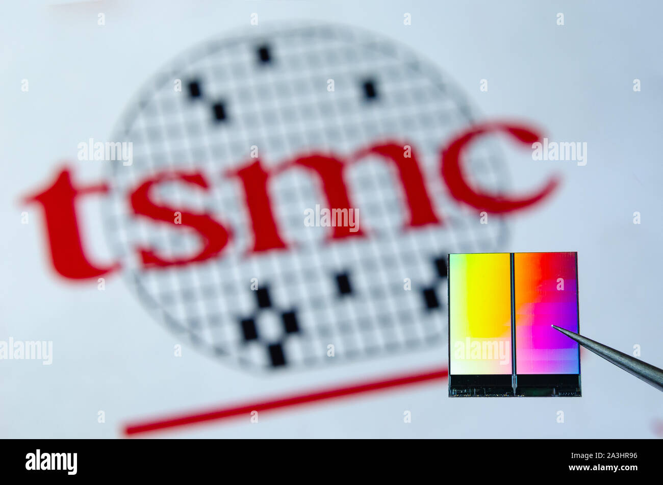 La photo en gros plan de puce (aka puce semi-conductrice, dispositif semi-conducteur, Circuit intégré) tenir à pincettes avec TSMC logo sur un arrière-plan. Banque D'Images