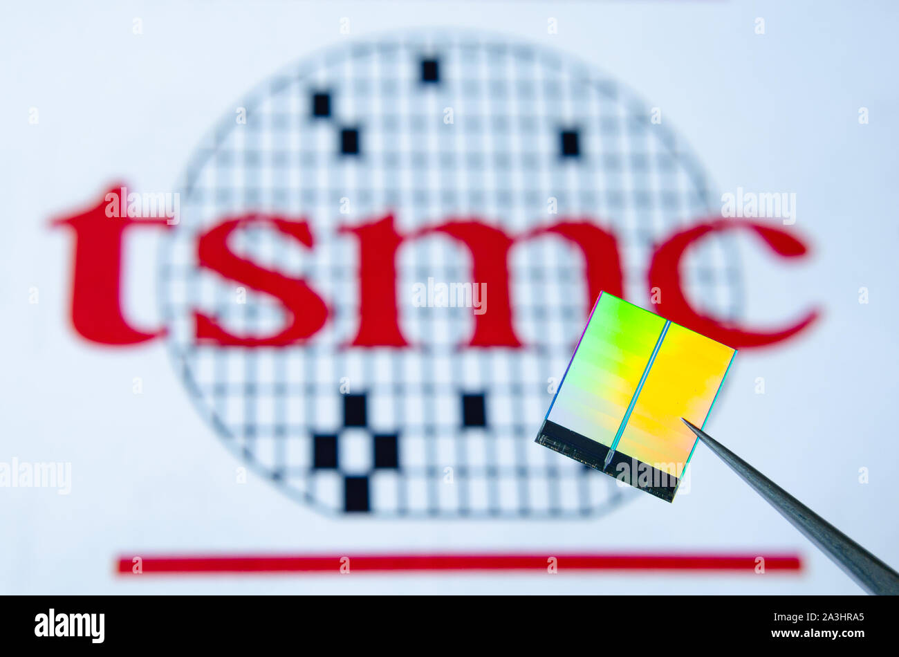 La photo en gros plan de puce (aka puce semi-conductrice, dispositif semi-conducteur, Circuit intégré) tenir à pincettes avec TSMC logo sur un arrière-plan. Banque D'Images