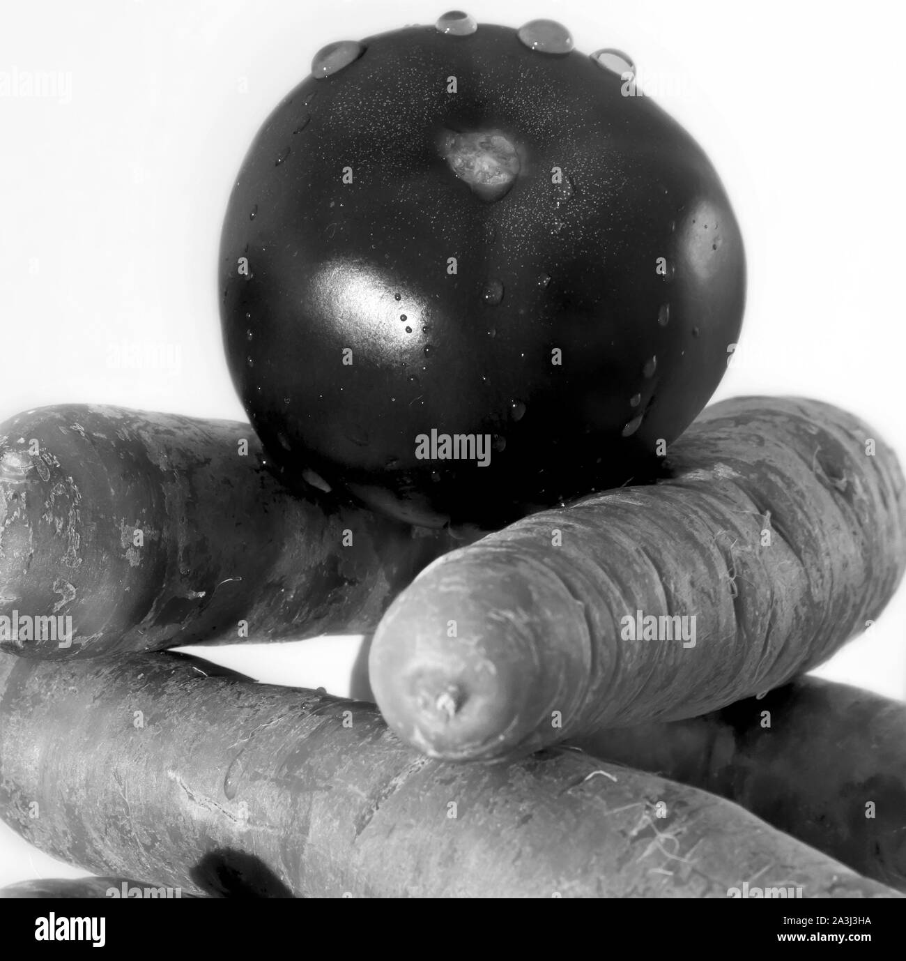 Une tomate sur quelques carottes. Photo en noir et blanc. Banque D'Images