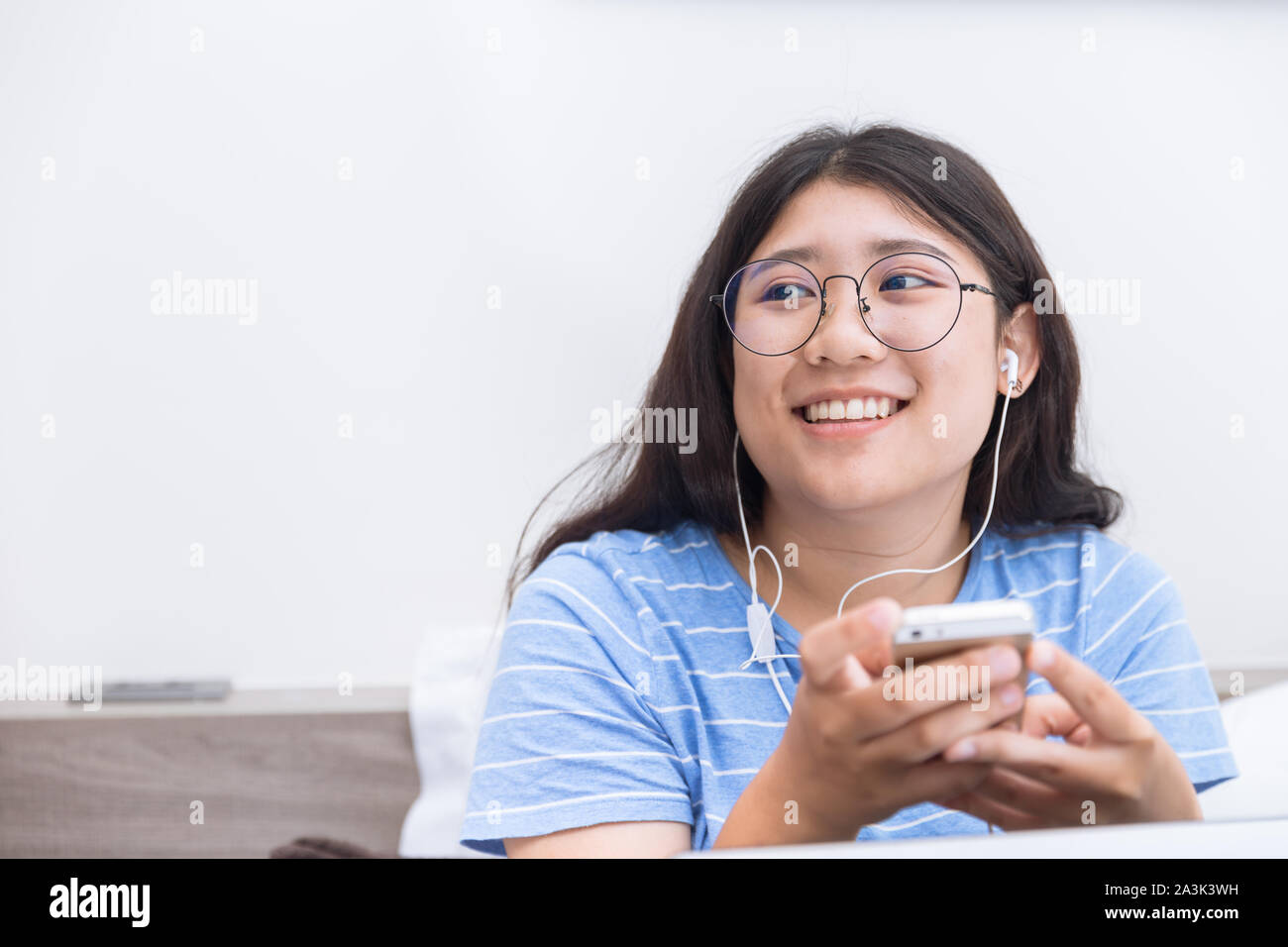 Jeune fille asiatique teen student using smartphone listening music sourire heureux vous détendre sur ben à holiday Banque D'Images