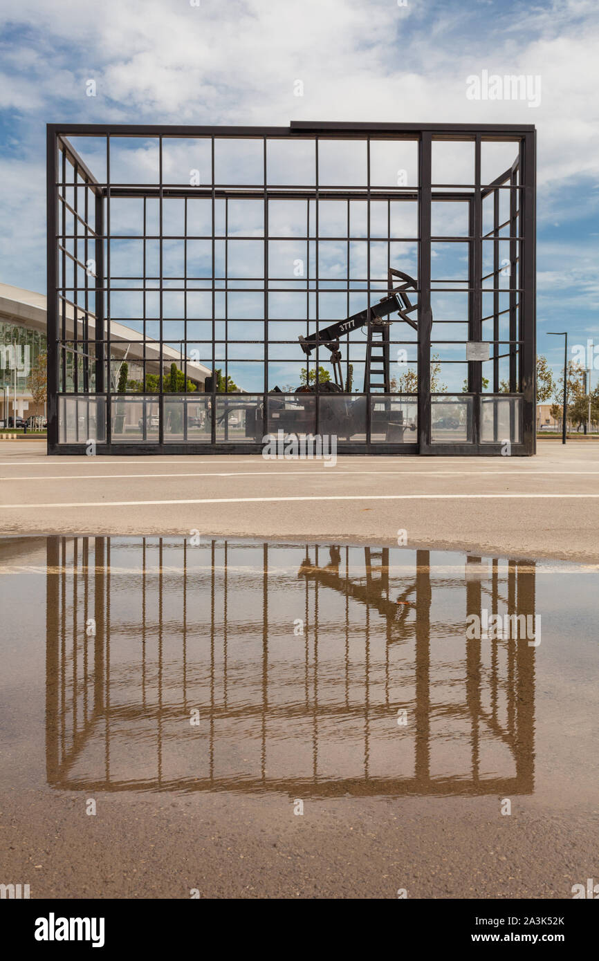 Baku, Azerbaïdjan - septembre 2019, puits de pétrole en cage en métal avec réflexion sur l'eau. Pompe à huile. Banque D'Images