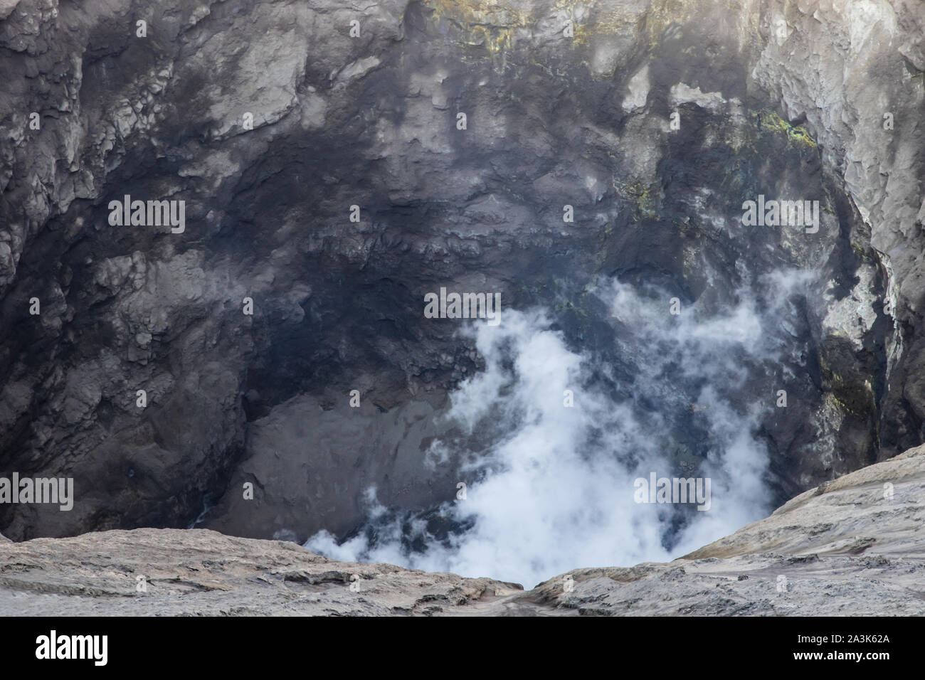 Gros plan de l'intérieur du cratère du Mont Bromo, Java Est, Indonésie. Gaz volcanique blanche passant de ci-dessous. Soufre jaune visible dans la roche. Banque D'Images