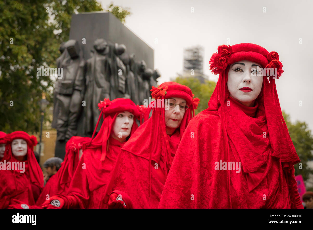 Whitehall, Londres, Royaume-Uni. - 7 octobre 2019 - XR ptotests - rouge 'Brigade' art group, au cours d'une performance de rue, 'la femme de guerre Warld II' en arrière-plan Banque D'Images