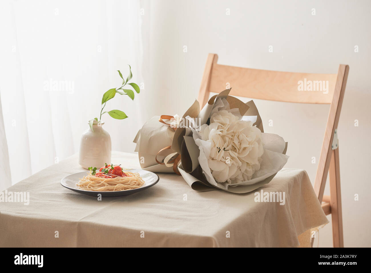 Des pâtes avec sauce ragoût sur plaque sur tableau blanc vintage avec une passoire et fleurs Banque D'Images