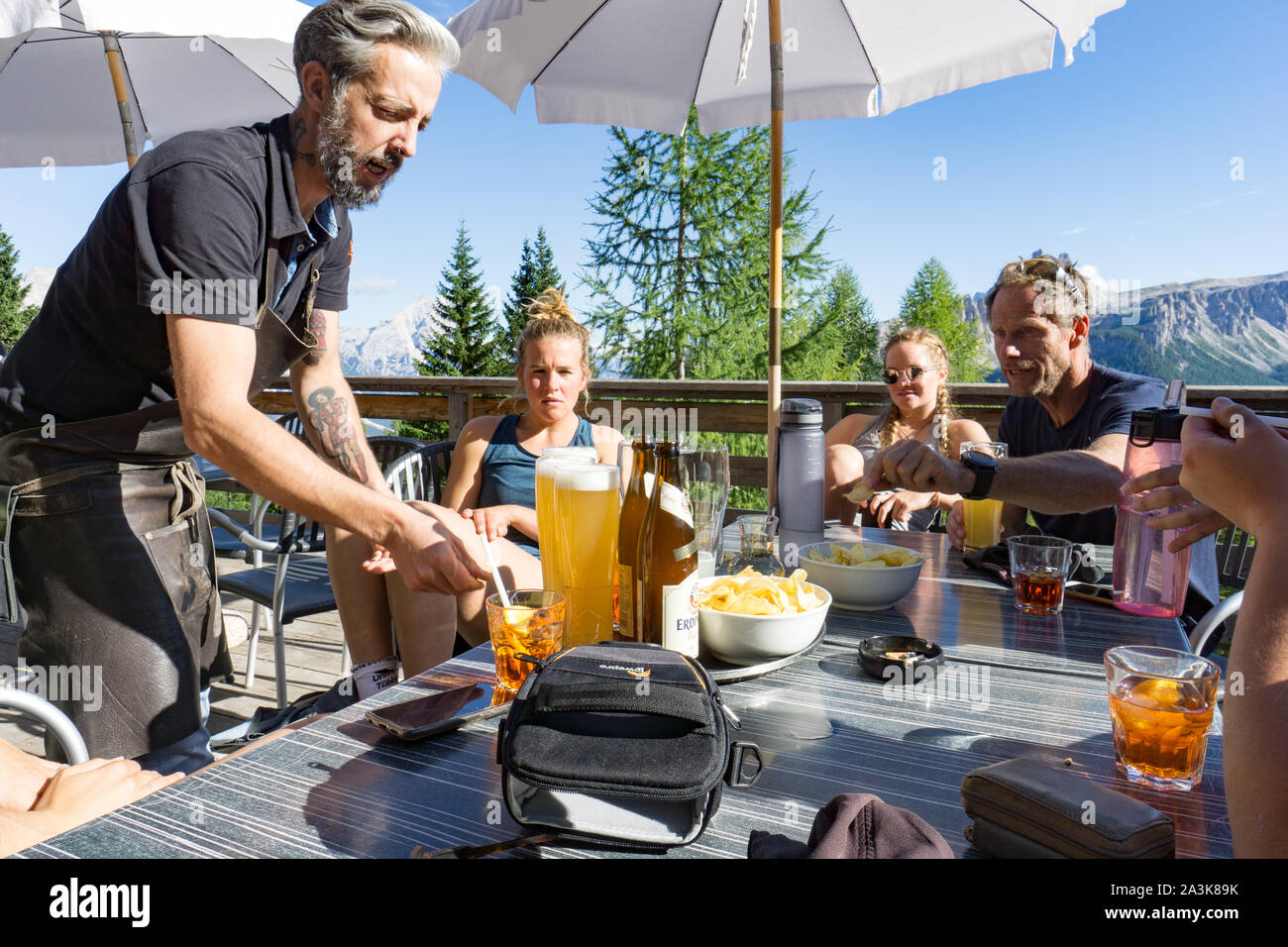 Cortina d'Ampezzo, Belluno / Italie - 3 septembre 2019 - femme d'escalade et leur guide de montagne se détendre dans un bar avec bière et chips après une dure ascension Banque D'Images
