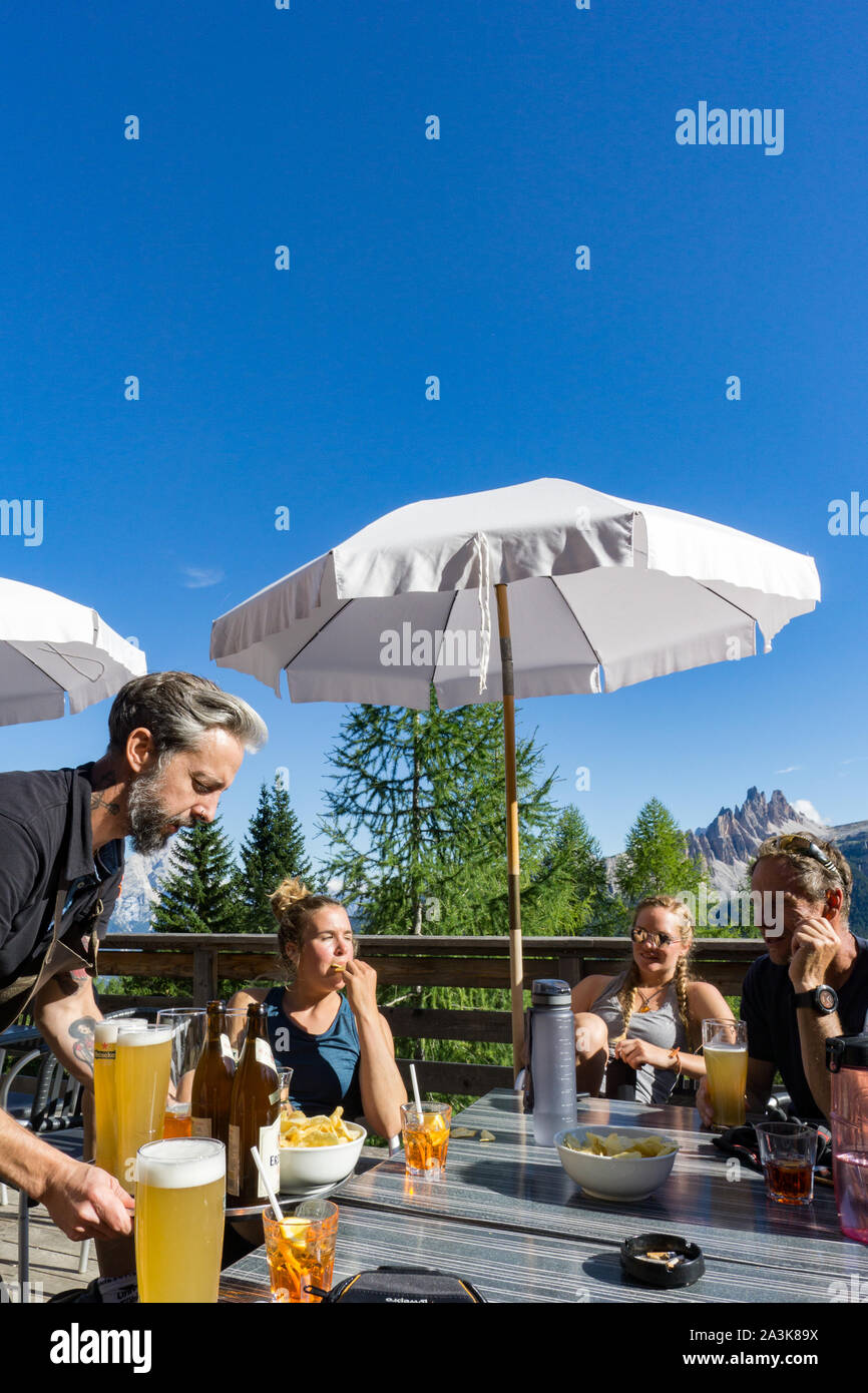 Cortina d'Ampezzo, Belluno / Italie - 3 septembre 2019 - femme d'escalade et leur guide de montagne se détendre dans un bar avec bière et chips après une dure ascension Banque D'Images
