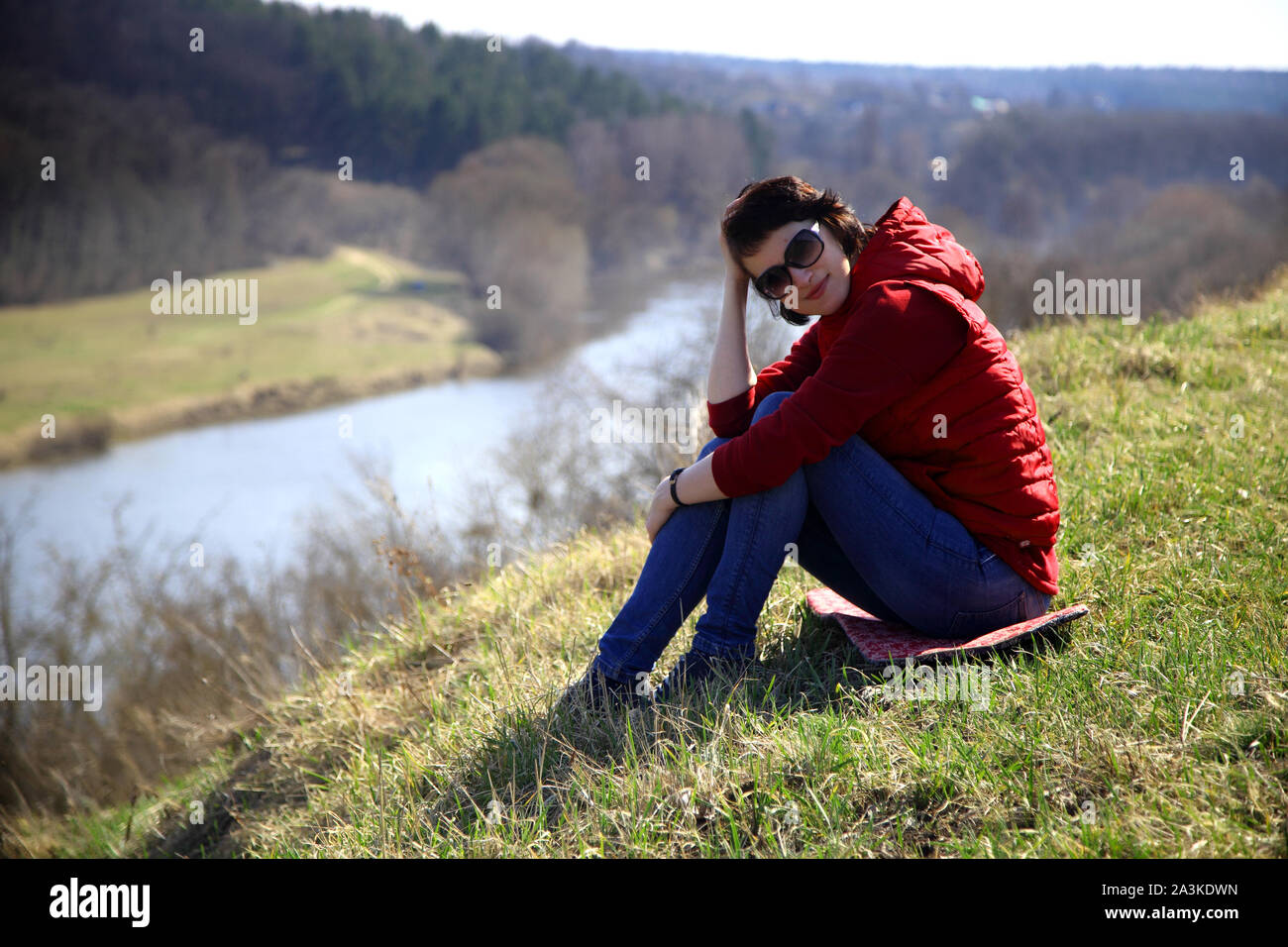 Une fille recueille des perce-neige dans la forêt. Belle jeune femme se baigne dans les rayons de soleil du printemps dans une clairière dans la forêt. Banque D'Images