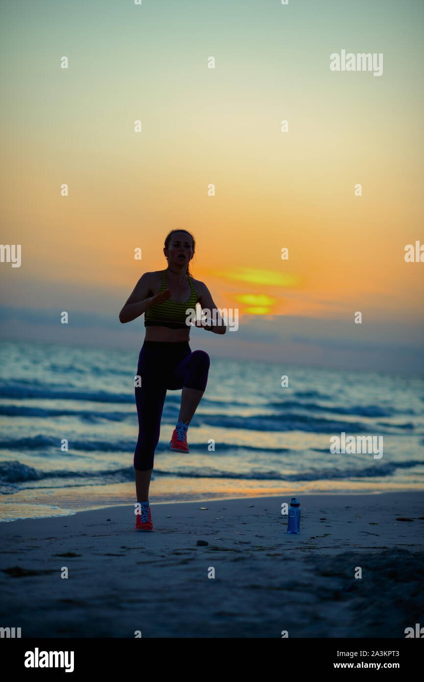 Silhouette de femme en fit sports vêtements de sport sur le bord de la mer dans la soirée de formation. Banque D'Images