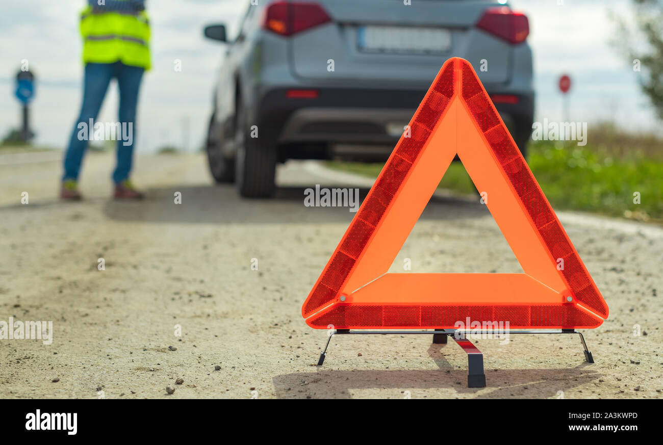 Panne du véhicule et le triangle sur la route, la femme à l'aide de téléphone pour demander de l'aide et l'assistance routière Banque D'Images