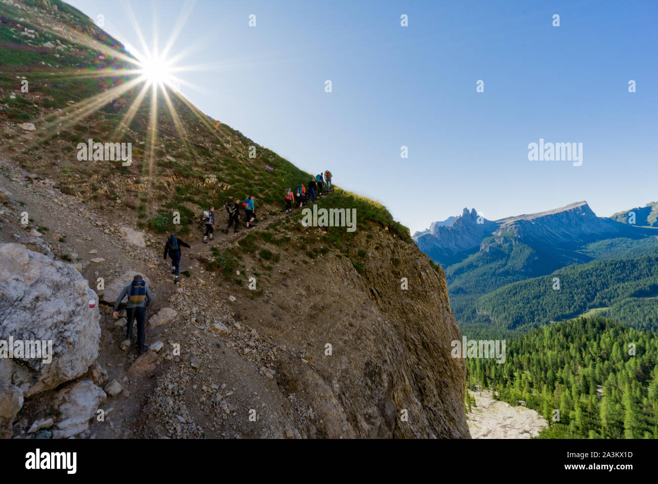Grand groupe de jeunes randonneurs qui monte un sentier de randonnée escarpé avec le soleil qui brille au-dessus d'eux et vue fantastique sur le paysage de montagne derrière Banque D'Images