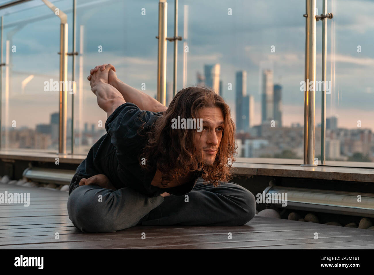 Man practicing yoga athlétique attrayant dans le centre d'affaires avec une belle vue sur une ville de gratte-ciel. Young et méditant à diner Banque D'Images