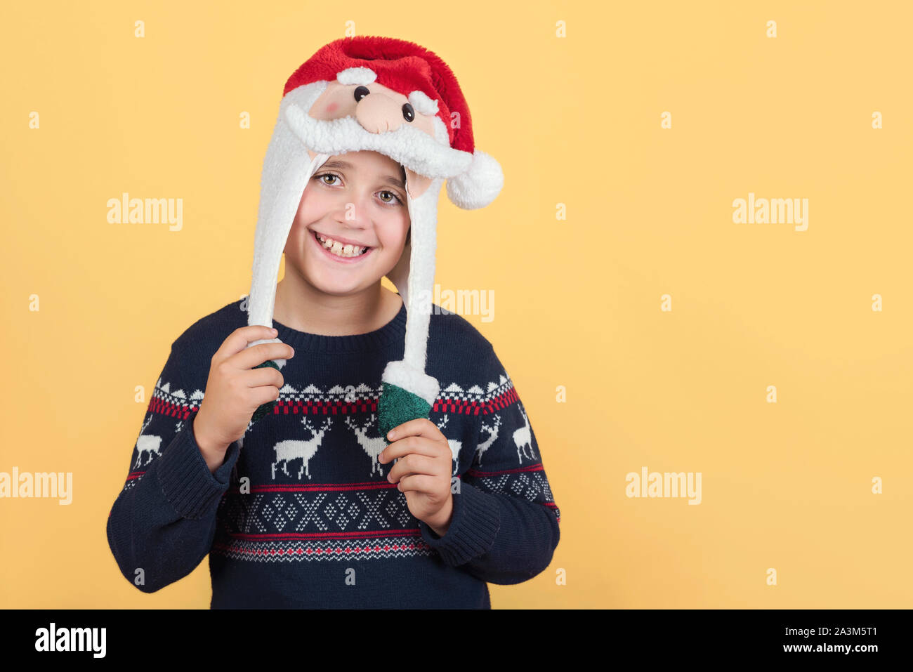 Smiling Child Wearing Christmas Santa Claus Hat sur fond jaune Banque D'Images