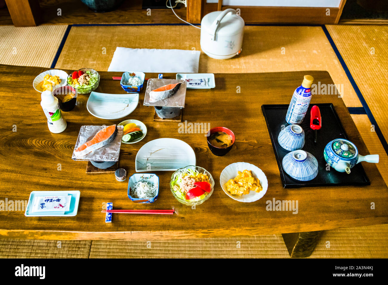 Ichi-ju-san-sai, un petit-déjeuner traditionnel japonais composé d'une soupe miso et de plusieurs petites garnitures, est disposé sur une table basse en bois au Ryokan Izu Makiba, Nishiizu-Cho, préfecture de Shizuoka, Japon. Du riz, du saumon grillé, des légumes marinés et du thé sont disposés sur le sol en tatami. Banque D'Images