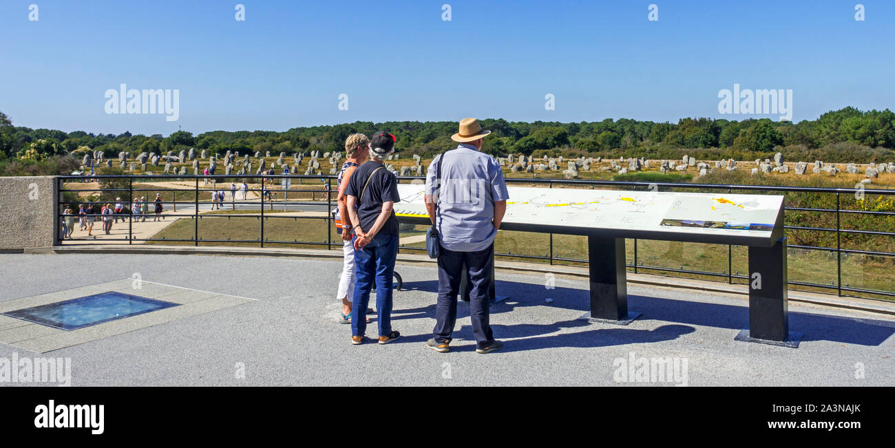 Les touristes à la recherche de personnes âgées de plus de pierres du Ménec alignements à partir de la terrasse panoramique de la Maison des mégalithes de Carnac, Bretagne, France Banque D'Images