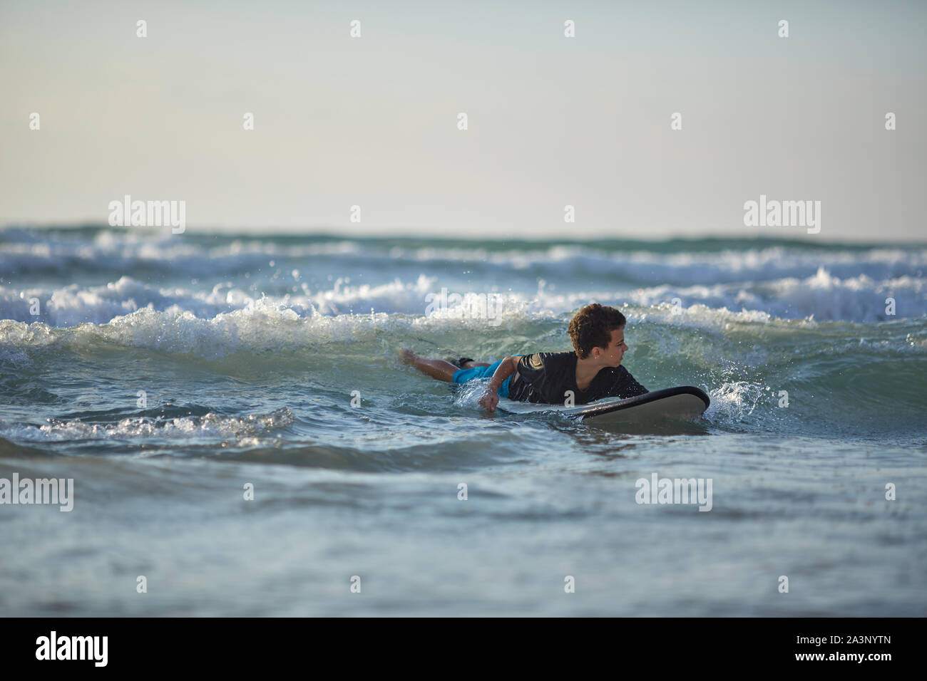 Petit garçon de surf sur une planche de surf dans l'océan indien. Banque D'Images