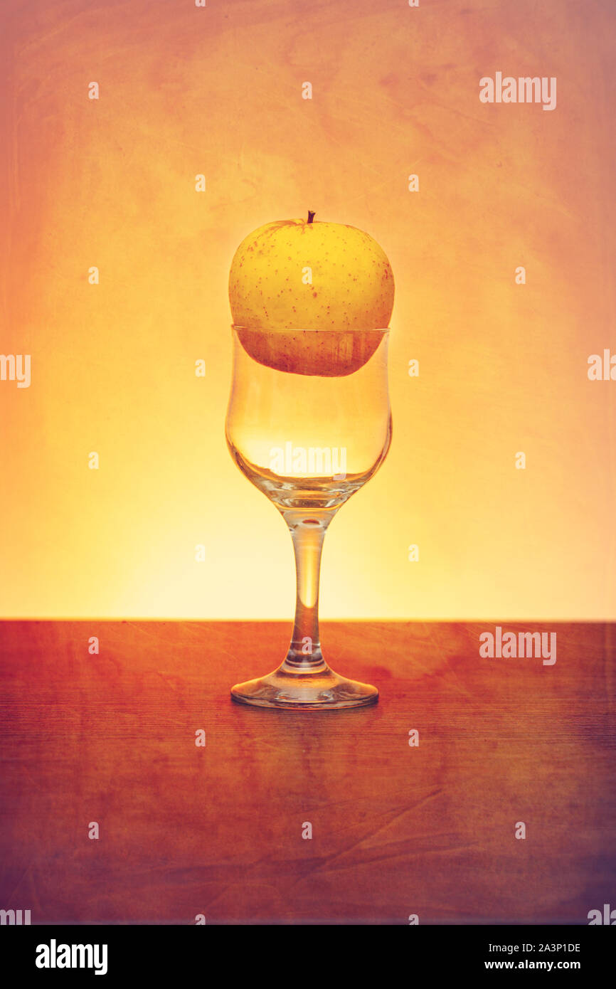 Idée conceptuelle de pomme d'or dans le verre de cidre comme matières premières au lieu de produit final à l'aide du filtre rétro Banque D'Images