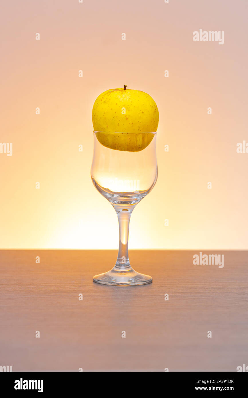 Idée conceptuelle de pomme d'or dans le verre de cidre comme matières premières au lieu de produit final Banque D'Images