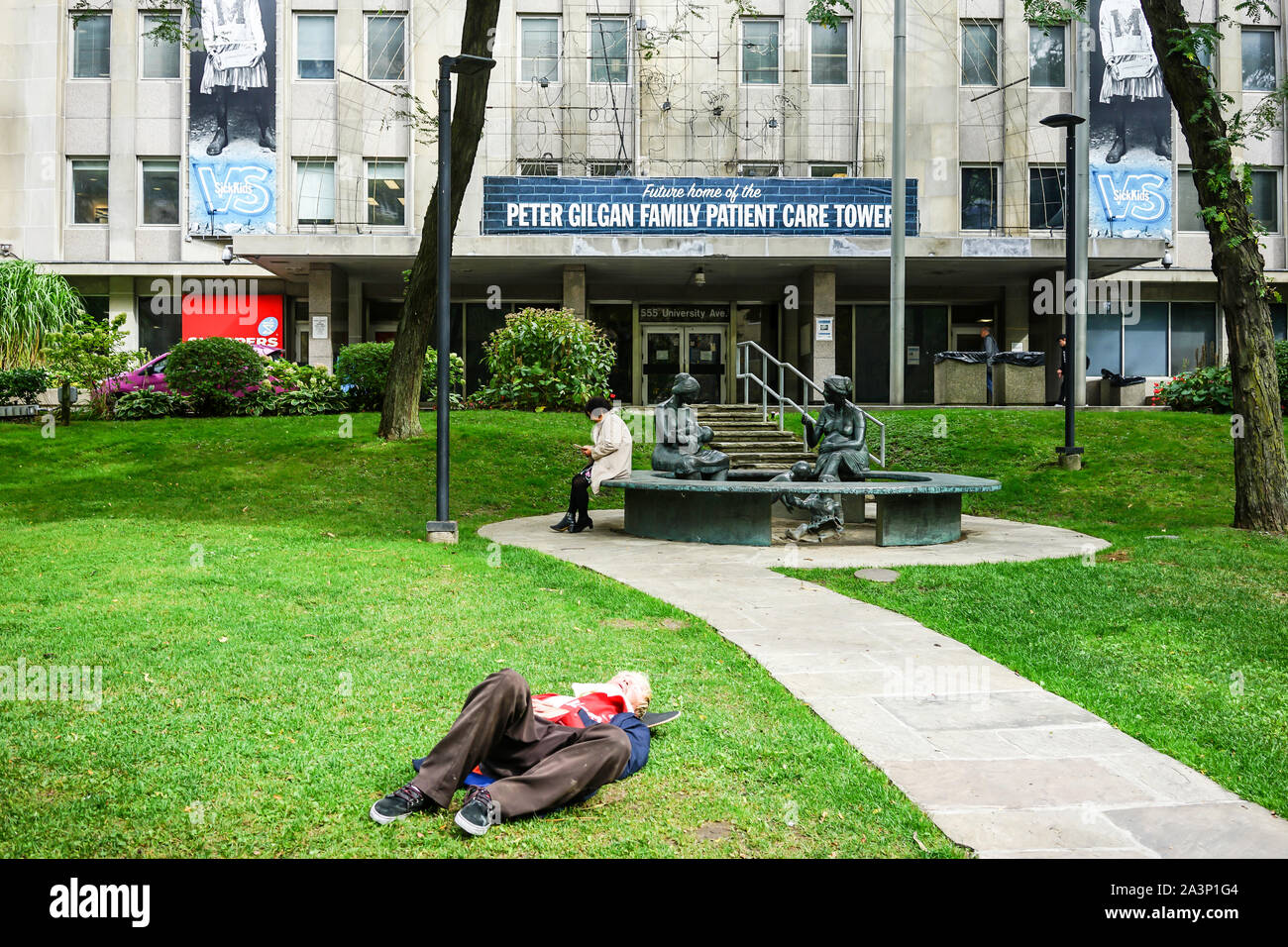 L'homme se reposant sur des pelouses en de de l'Hôpital pour enfants malades de Toronto, Ontario, Canada Banque D'Images