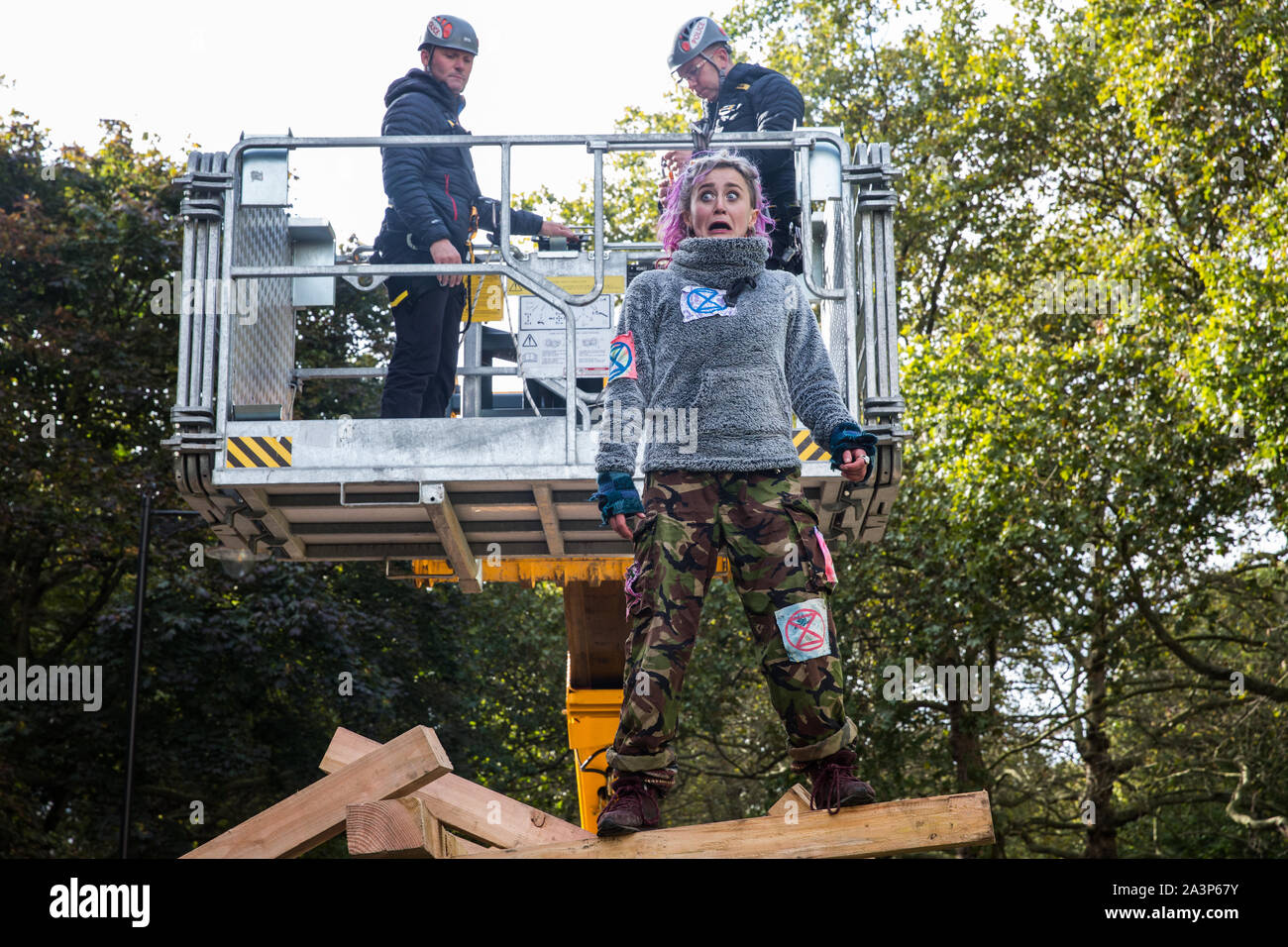 Londres, Royaume-Uni. 9 octobre, 2019. Un activiste climatique de l'Extinction, rébellion, feint l'horreur en tant qu'agents de police sur une approche à partir de la grue JCB derrière pour essayer de l'arrêter après qu'elle avait grimpé en haut d'une structure en bois pour bloquer la cage à pied sur le troisième jour de la rébellion des protestations. Credit : Mark Kerrison/Alamy Live News Banque D'Images