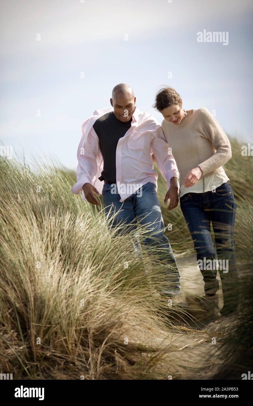 Smiling young couple marchant côte à côte à travers les dunes de sable. Banque D'Images