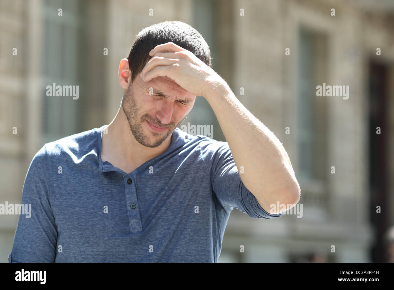 A souligné l'homme adultes souffrant des maux de tête se plaignent de toucher dans la rue Banque D'Images
