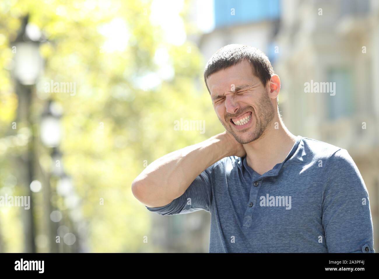 A souligné l'homme adultes souffrant des douleurs du cou tout seul dans la rue Banque D'Images