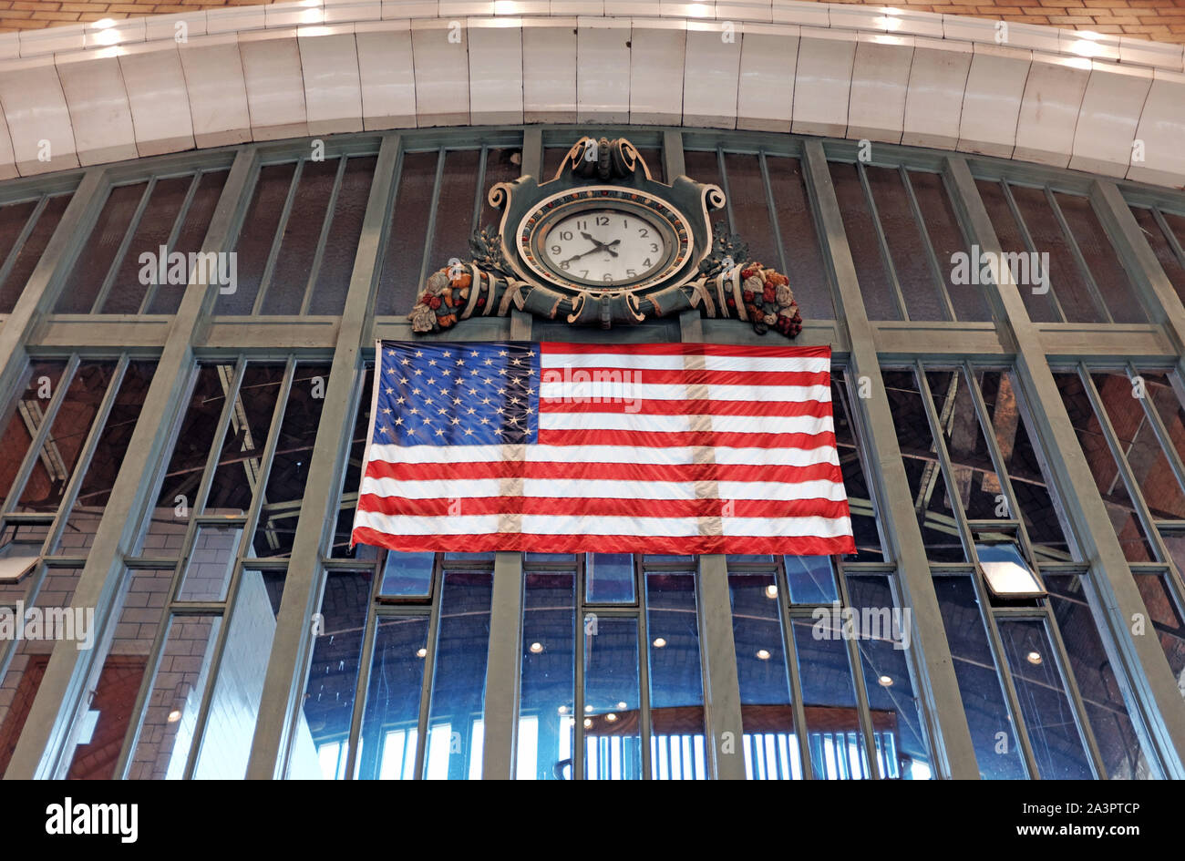 Un drapeau américain est suspendu au-dessus du côté ouest de l'intérieur du marché alors qu'un réveil historique au-dessus montre le temps dans ce site historique de Cleveland, Ohio, USA. Banque D'Images
