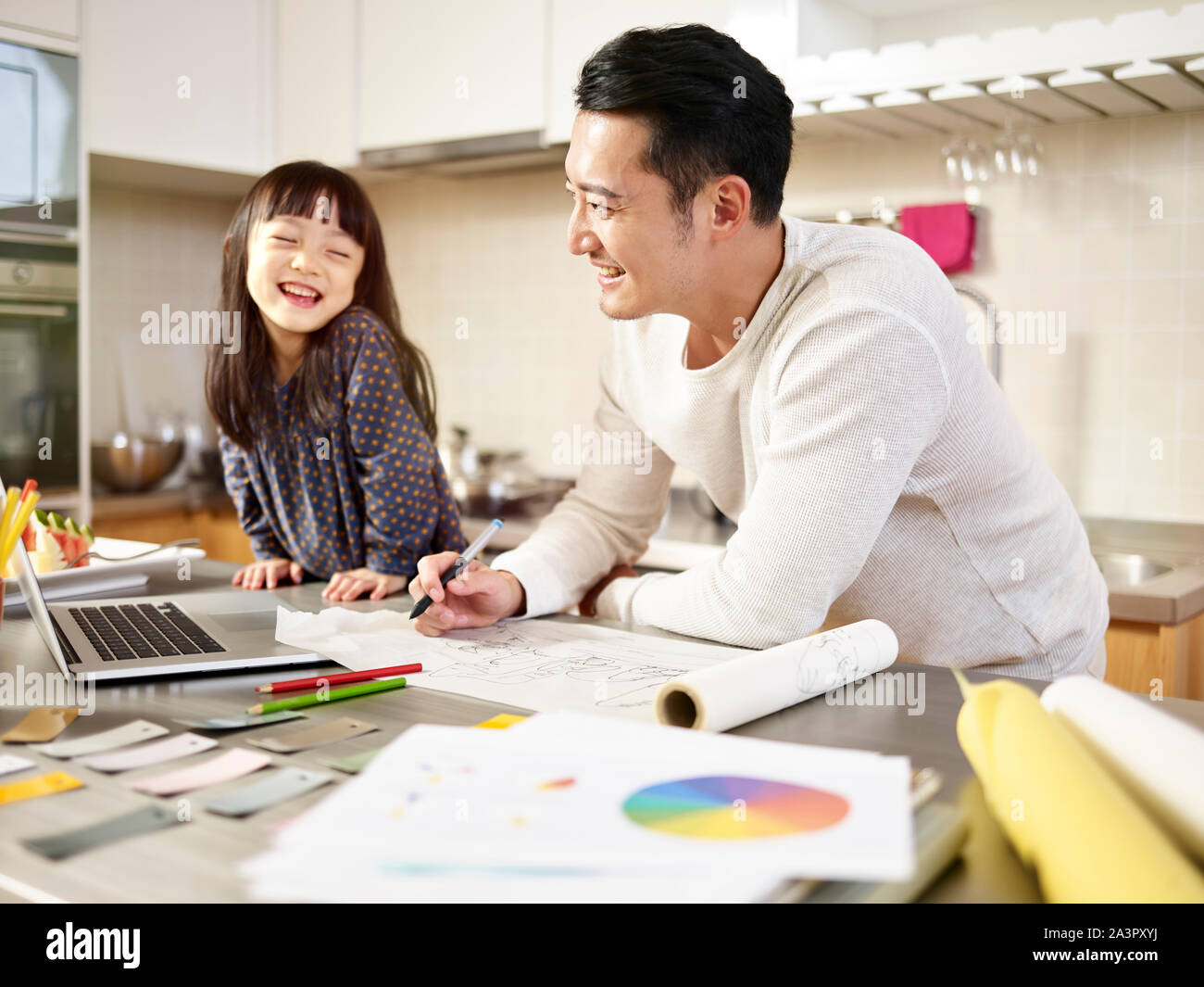Jeune designer asiatique père travailler à la maison tout en prenant soin de sa fille. Banque D'Images