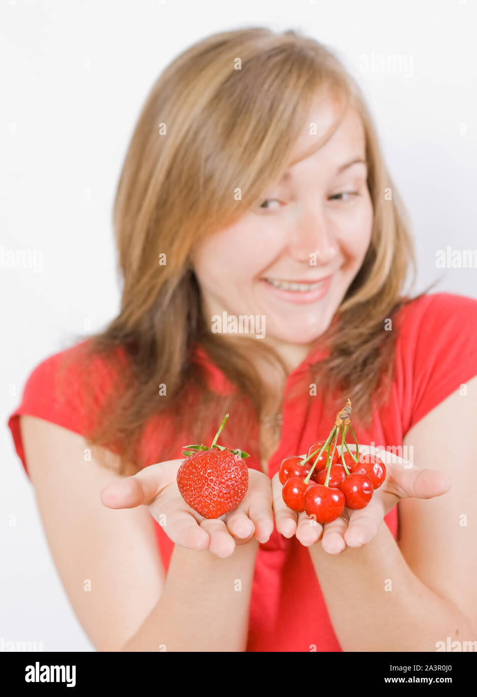 Jeune fille douce montrant le rouge cerise et fraise Banque D'Images