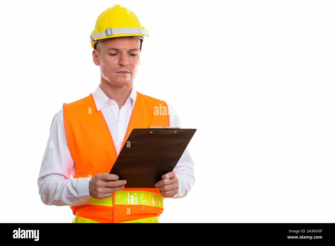 Studio shot of young handsome man construction worker reading sur Banque D'Images
