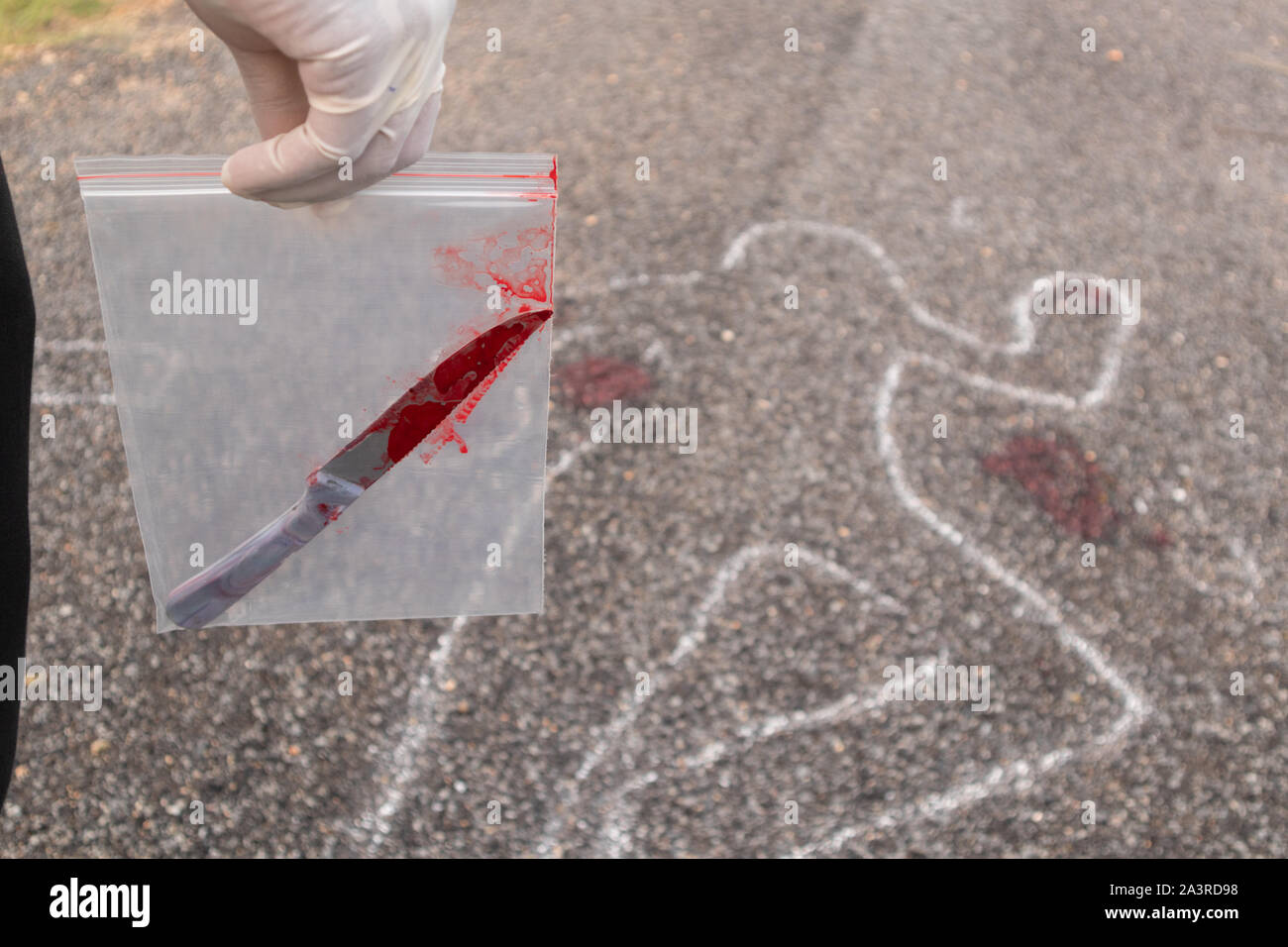Notion de crime scene investigation, détective ou enquêteur holding Sachet de preuves avec couteau sanglant en sac et chalk a décrit comme une zone de corps morts Banque D'Images